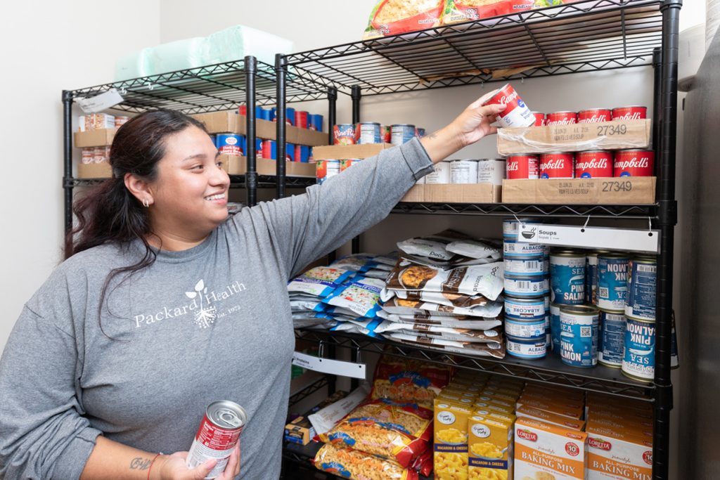 Woman taking cans of food from pantry.