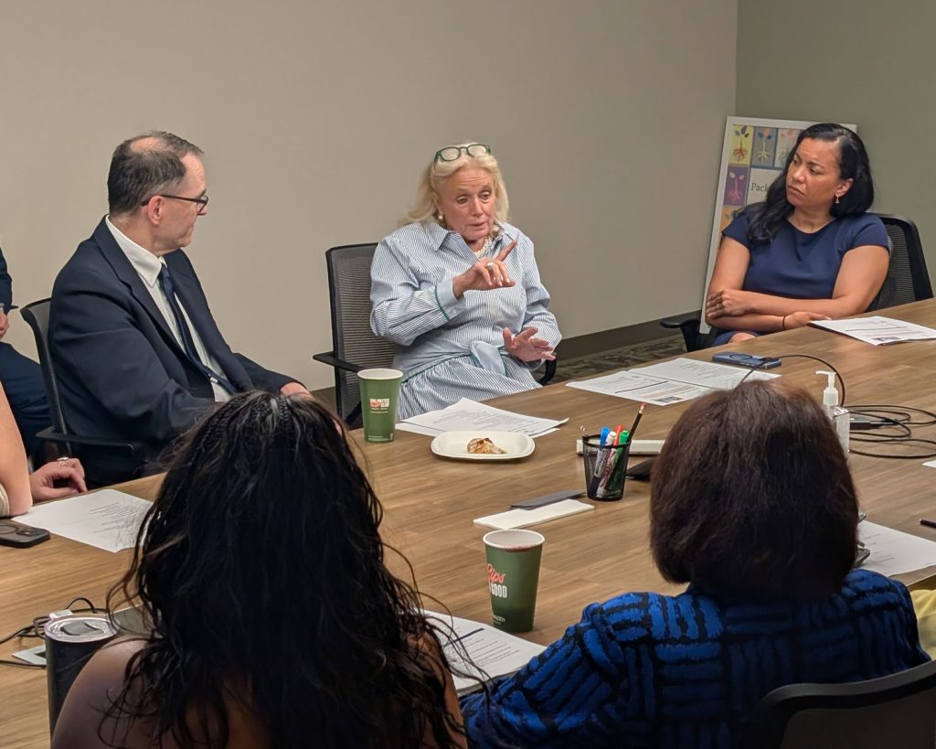 Representatives Dingell and Mejia at a conference table speaking with Packard Health staff and board members