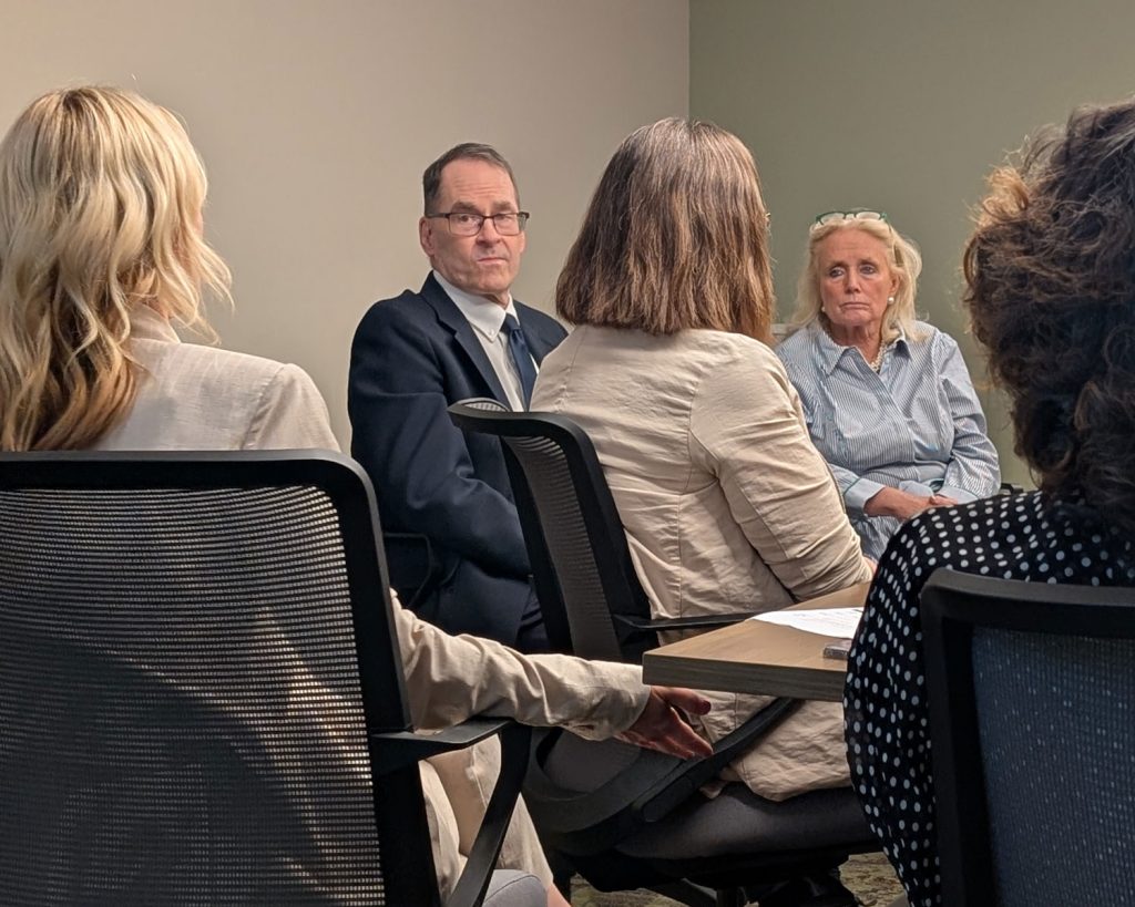 Representative Dingell at a conference table speaking with Packard Health staff