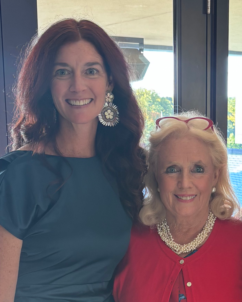 A tall brown-haired woman standing next to a shorter blonde-haired woman.